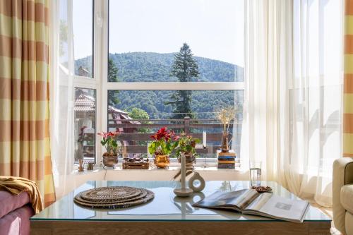 a living room with a large window and a table at Roberto Hotel in Sinaia