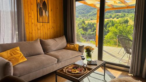 a living room with a couch and a large window at Varadeo Hill Resort in Şuncuiuş
