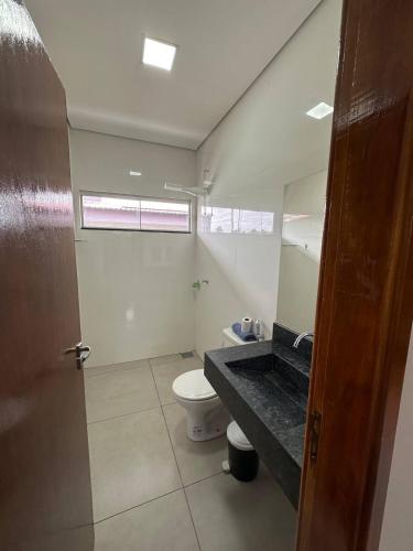 a bathroom with a toilet and a sink and a mirror at Casa Piscina Centro BonitoMS in Bonito
