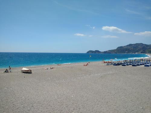 a beach with a lot of people and the ocean at Polifemo in Letojanni