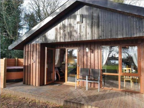 a wooden cabin with glass doors and a deck at Willow Lodge 13 Hot Tub in York