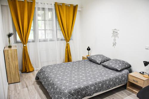 a bedroom with a bed and orange curtains at Spacieux F2 - Louvroil - Proche Belgique in Louvroil
