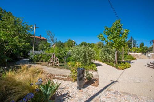 a garden with trees and plants on a sidewalk at Mas J des Sens - petit dej compris in Le Val
