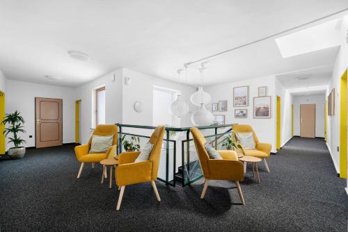 a waiting room with yellow chairs and a table at Penzion Village Peace #29 by Goodnite cz - U Libušky in Brno