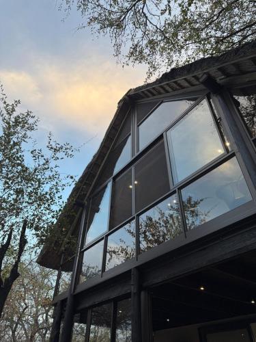 a building with glass windows on the side of it at Veni Vidi Amavi Luxury Safari Treehouse in Marloth Park