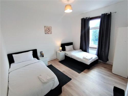 Un dormitorio con dos camas y una ventana en 4 Bedroom House 8min walk to EastHam Station, en Londres