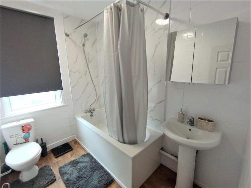 Un baño con lavabo, inodoro y ducha. en 4 Bedroom House 8min walk to EastHam Station, en Londres