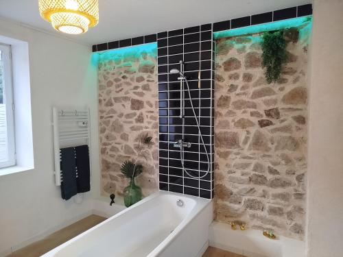 a bath tub in a bathroom with a stone wall at Parenthèse Aiyanna in Moux-en-Morvan