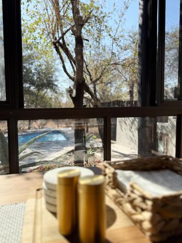 a table with a window looking out at a tree at Veni Vidi Amavi Luxury Safari Treehouse in Marloth Park