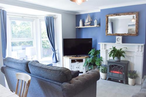 un salon bleu avec un canapé et une télévision dans l'établissement Turnstone - Suffolk Coastal Escapes, à Pakefield