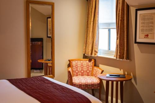 a bedroom with a bed and a chair and a window at The Red Lion Hotel in Hillingdon
