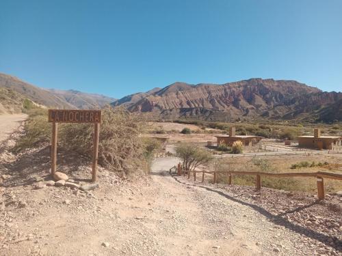 a dirt road with a sign in the desert at Cabañas La Nochera in Tilcara