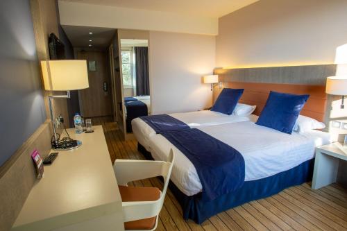 a hotel room with a large bed with blue pillows at Logis Hôtel & Restaurant - Les Tuileries in Féy