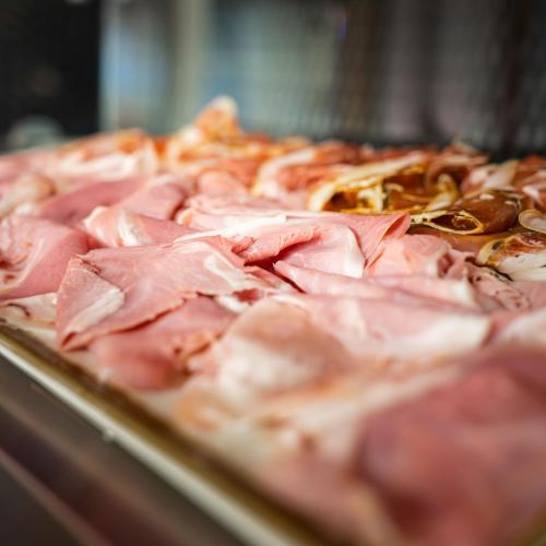 a close up of a pizza with ham and peppers at Logis Hôtel & Restaurant - Les Tuileries in Féy
