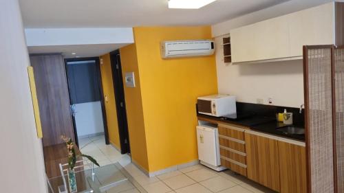 a kitchen with a yellow wall and a microwave at Beach Class Executive in Recife