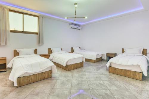 a room with four beds in it with a blue light at White Majorelle Casa Grande in Tamraght Ouzdar