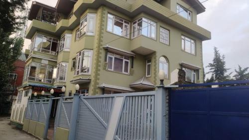 a yellow house with a blue fence in front of it at Hotel Indra in Srinagar