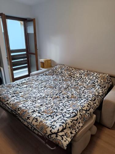 a bed in a room with a flowered blanket on it at Aurora Boreale studio - centro Aprica - parking in Aprica