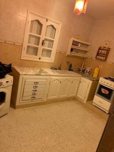 a kitchen with white cabinets and a sink and a stove at Villa flamant rose in Djerba