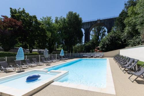 a swimming pool with chairs and a bridge in the background at Les Rives d’Auzon confort 8 pers in Lavilledieu