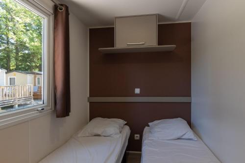 two beds in a room with a window at Les Rives d’Auzon confort 8 pers in Lavilledieu