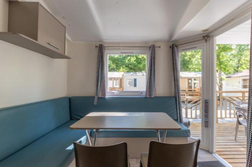 a dining room with a table and chairs and a balcony at Les Rives d’Auzon confort 8 pers in Lavilledieu
