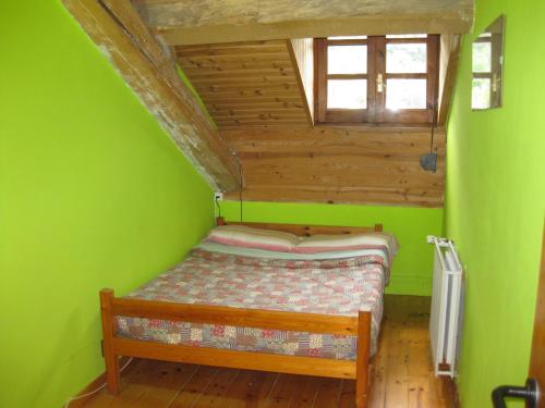 a small bedroom with a bed in a green room at Albergue Pájaro Loco in Castejón de Sos