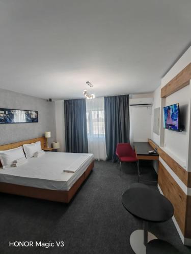 a hotel room with a bed and a desk and chair at Hanul Dintre Vii in Mărăşeşti