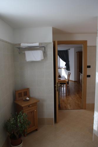 a bathroom with a door open to a room with a table at La Baita in Livinallongo del Col di Lana