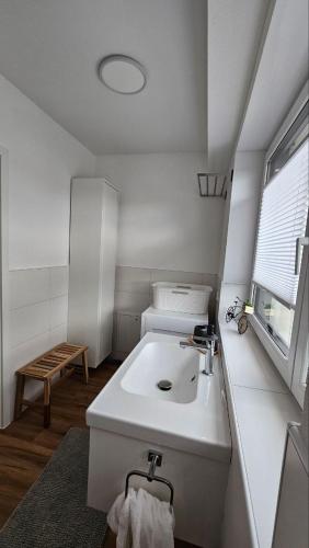 a white bathroom with a sink and a window at FeWo nähe Europapark Fabio in Schwanau