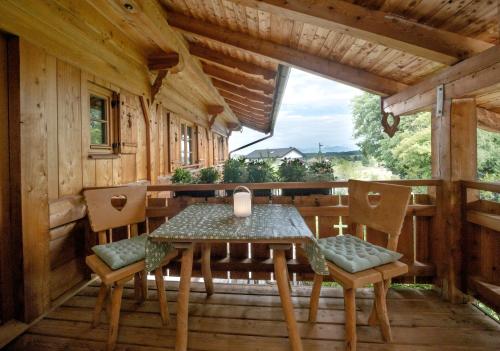 a table and chairs on the porch of a cabin at Ferienwohnung Allgäutraum mit Bergblick in Oy-Mittelberg
