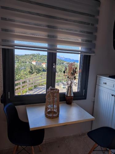a table with a window with a vase of flowers on it at Georgia's Dream House in Koprána