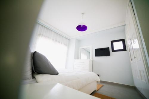 a white bedroom with a bed and a window at Villa Agloucenter in Zaouia Sidi Ouaggag