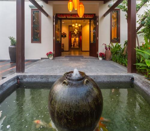 a vase in the water in front of a building at Cozy Savvy Hoi An - The Quintessence of Exquisite Retreat in Hoi An