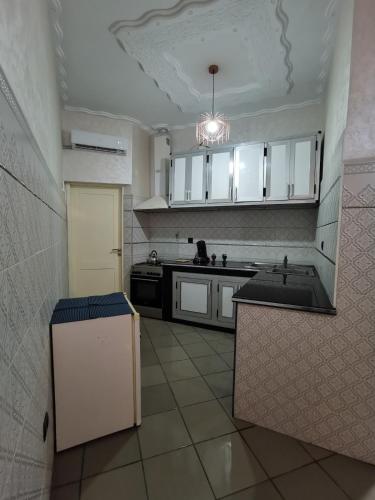a large kitchen with white cabinets and a tile floor at Family Time in Nador