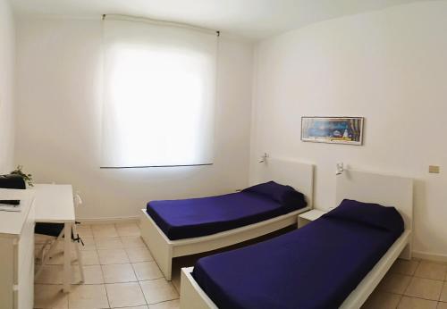 a room with two beds and a desk and a window at B&B accogliente a due passi dal metrò di Milano - Casa Adriana in Cologno Monzese