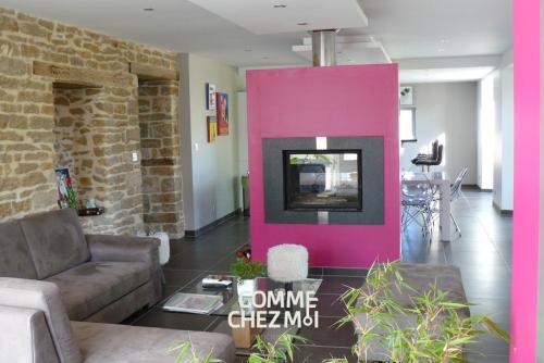 - un salon avec un mur rose et une télévision dans l'établissement Gîte Charmant D'Olympe, à Graffigny-Chemin