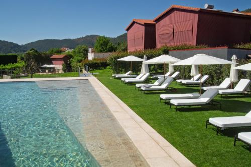 a row of chairs and umbrellas next to a swimming pool at Quintãs Farm Houses in Arouca