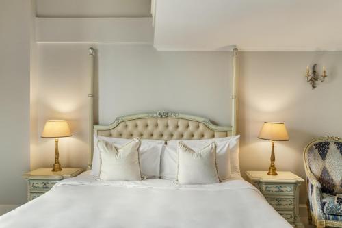 a bedroom with a white bed with two lamps and a chair at Hotel Bardot Boutique in Panama City