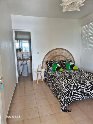 a bedroom with a bed with a black and white comforter at F2 magnifique vue mer in Le Robert