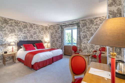 a bedroom with a bed and a table with a lamp at Le Manoir De La Poterie & Spa in Cricquebœuf