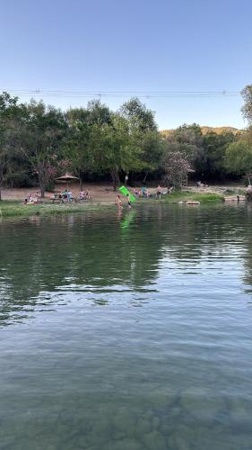 a large body of water with people sitting on the shore at Habitación jardín junto al río in El Colmenar