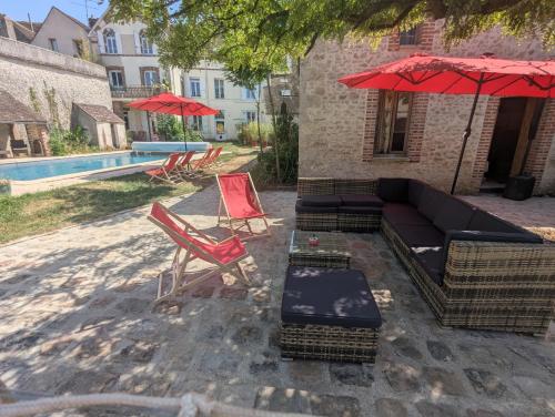 a patio with a couch and chairs and an umbrella at Grand Deluxe Poule Noire in Égreville