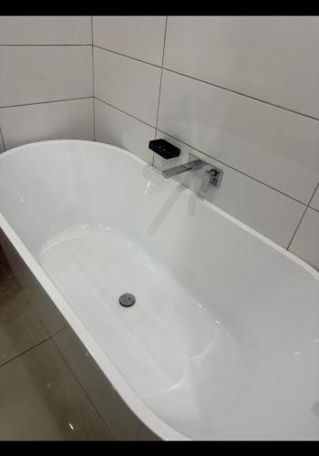 a white bath tub in a white tiled room at Tamboti in Vosburg