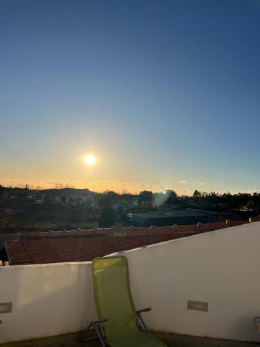 a green chair sitting on a ledge with the sunset at Casa do Caracol in Oliveira de Azemeis