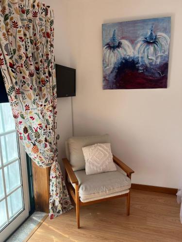 a living room with a chair and a curtain at Casa do Caracol in Oliveira de Azemeis