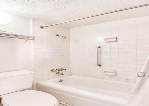 a bathroom with a white tub and a toilet at OYO Hotel Jackson North I-55 in Jackson
