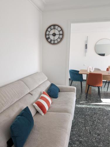 a living room with a couch with a clock on the wall at "La Planque" T4 en plein centre, calme et lumineux - Terrasse & parking in Valence