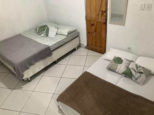 two twin beds in a room with a mirror at Rota Itacaré Surf Hostel in Itacaré