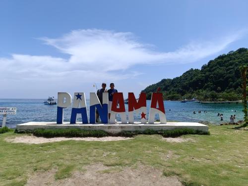 two people standing on top of a sign at the beach at hotel vivo por ella in Capurganá